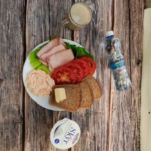 Zdjęcie przedstawia Dietę z ograniczeniem łatwoprzyswajalnych węglowodanów: Masło extra 82% Szynka Piastowska Pomidor Kawa zbożowa z mlekiem Chleb Graham Jogurt typu islandzkiego naturalny Skyr Woda mineralna Sałata zielona Pasta z twarogu i koncentratu